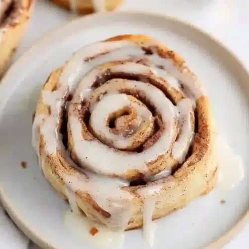 Warm tortilla cinnamon rolls topped with sweet glaze on a serving plate