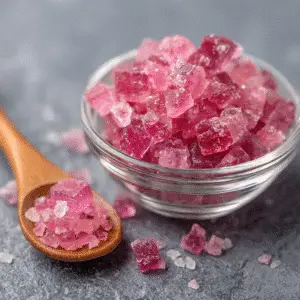Coarse pink Himalayan salt in a bowl with a wooden spoon.