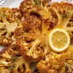 Delicious grilled cauliflower steaks seasoned with spices and lemon, served on a plate.