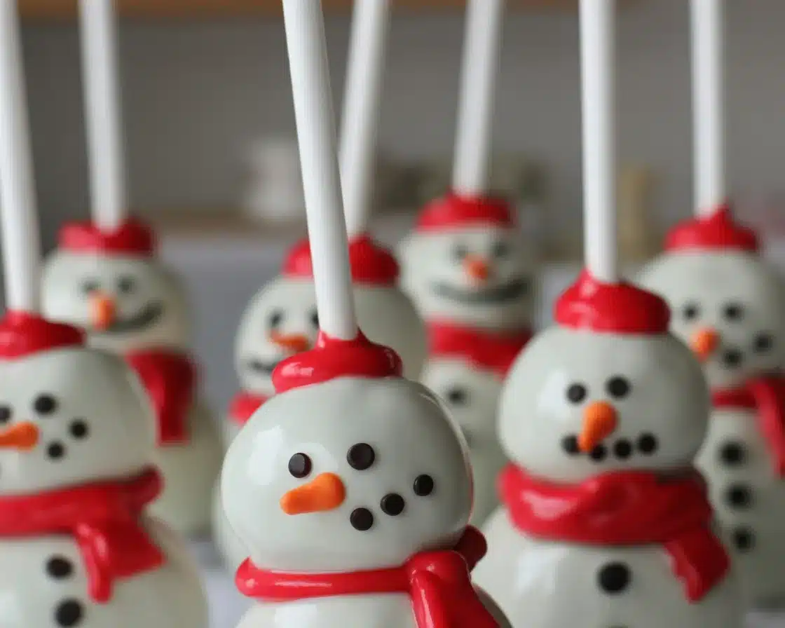 Adorable Snowman Cake Pops decorated with candy and sprinkles for Christmas.