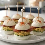Deviled egg bacon sliders with creamy yolk filling on egg white buns